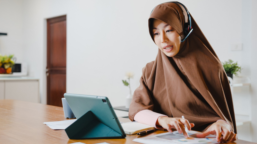 Certified Teachers Who Master Pedagogy, Not Just Memorization feature image by qibla academy featuring a female Muslim Quran teacher wearing a hijab and headset while teaching via a tablet.