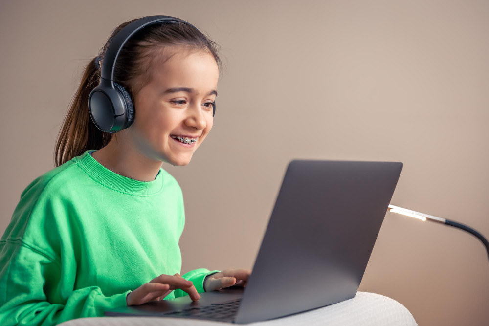 What Makes the Best Online Hifz Program for Children feature image by qibla academy featuring a smiling young girl with braces wearing headphones and using a laptop.
