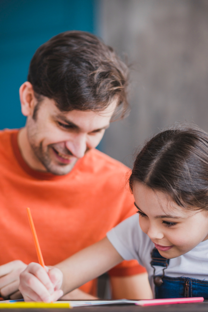 When to Seek External Guidance to Optimize Your Child's Roadmap feature image by qibla academy featuring a smiling father watching his young daughter write with a pencil.